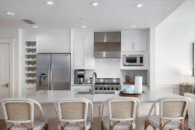 a kitchen with white cabinets and a table with chairs at Gulf Front - Large Pool - Bikes - Gated Community in Inlet Beach