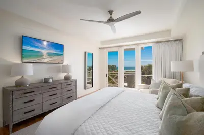 a white bedroom with a large bed and a tv at Gulf Front - Large Pool - Bikes - Gated Community in Inlet Beach