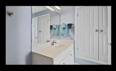 a white bathroom with a sink and a mirror at Beautiful Beachfront Views - The Retreat at Emerald Isle in Panama City Beach