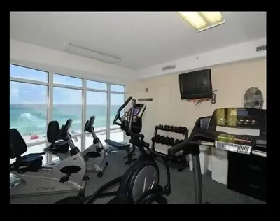 a gym with cardio equipment in a room with windows at Beautiful Beachfront Views - The Retreat at Emerald Isle in Panama City Beach