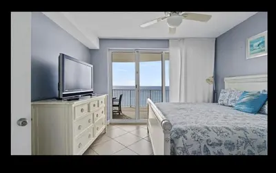 a bedroom with a bed with a television and a balcony at Beautiful Beachfront Views - The Retreat at Emerald Isle in Panama City Beach