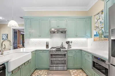 a kitchen with green cabinets and white counter tops at Sugar Beach Cottage in Inlet Beach