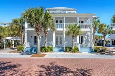 a white house with palm trees in front of it at Sugar Beach Cottage in Inlet Beach
