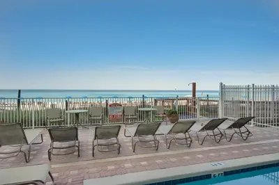a row of chairs and tables next to a pool at Beachfront Bliss Luxe 3BR Condo at Marisol Complex in Panama City Beach