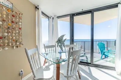 a dining room with a glass table and chairs at Sunbird 1204W 'Humphries Hideaway' in Panama City Beach