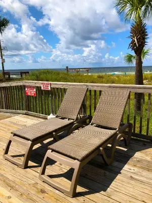 two chairs sitting on a deck near the beach at Sunbird 1204W 'Humphries Hideaway' in Panama City Beach