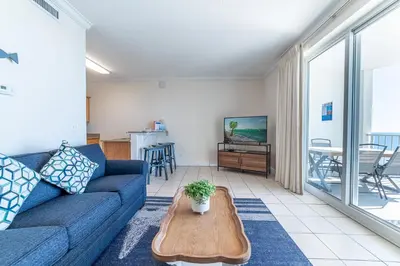 a living room with a blue couch and a table at Twin Palms 1903 'No Bad Days' in Panama City Beach