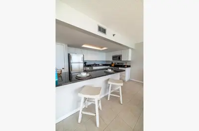 a kitchen with white cabinets and white stools at Edgewater 3-1113 'Ocean's 1113' in Panama City Beach