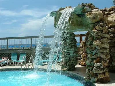 a fountain in a swimming pool next to a rock wall at Edgewater Villa 3001 'Vitamin Sea' in Panama City Beach