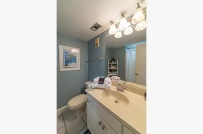 a bathroom with a sink and a toilet and a mirror at Edgewater 3-0404 'Isle Be Back' in Panama City Beach