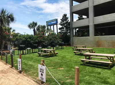 a group of picnic tables on the grass in front of a building at Shores of Panama 1520 'Thirsty Turtle' in Panama City Beach