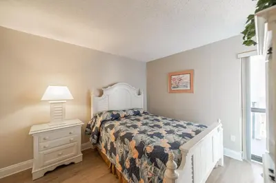 a bedroom with a bed and a lamp and a window at Edgewater 1-0502 'Island Paradise' in Panama City Beach