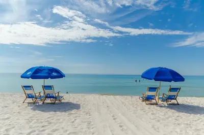 two blue chairs and two umbrellas on a beach at Edgewater 2-1202 'Shore Fun Penthouse' in Panama City Beach