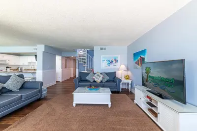 a living room with a couch and a tv at Edgewater 2-1202 'Shore Fun Penthouse' in Panama City Beach