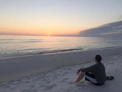 a man sitting on the beach watching the sunset at Edgewater L301 'The Nauti Starfish' in Panama City Beach