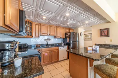 a kitchen with wooden cabinets and a stainless steel refrigerator at Edgewater L301 'The Nauti Starfish' in Panama City Beach