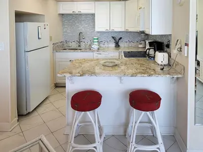 a kitchen with two red stools at a counter at Sunbird 0405E 'No Worries' in Panama City Beach