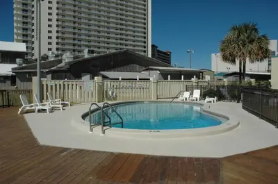 a large swimming pool with chairs and a building at Sunbird 0405E 'No Worries' in Panama City Beach