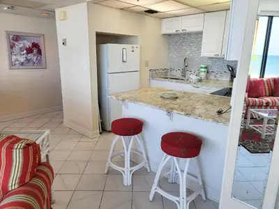 a kitchen with two stools and a counter with a refrigerator at Sunbird 0405E 'No Worries' in Panama City Beach