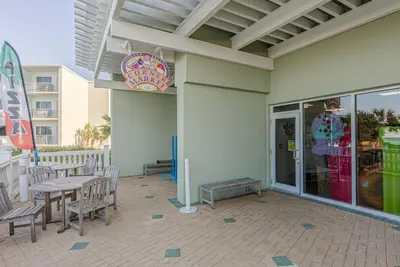 a patio with a table and chairs on a building at Boardwalk 0605 'Good Times & Tan Lines' in Panama City Beach