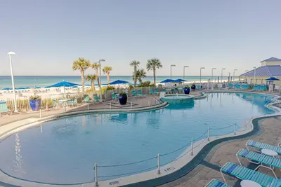 a large swimming pool with chairs and the beach at Boardwalk 0605 'Good Times & Tan Lines' in Panama City Beach