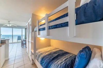 a bedroom with bunk beds and a balcony with the ocean at Boardwalk 0605 'Good Times & Tan Lines' in Panama City Beach