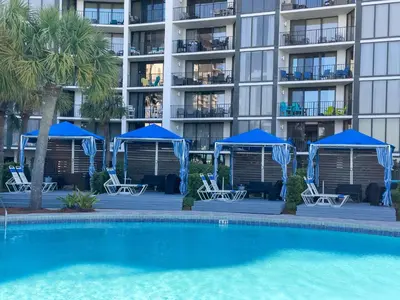a swimming pool with chairs and umbrellas in front of a building at Edgewater Villa 2708 'Lost Shaker of Salt' in Panama City Beach