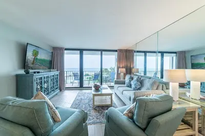 a living room with couches and a view of the ocean at Edgewater 1-0303 'Salty Sunsets' in Panama City Beach