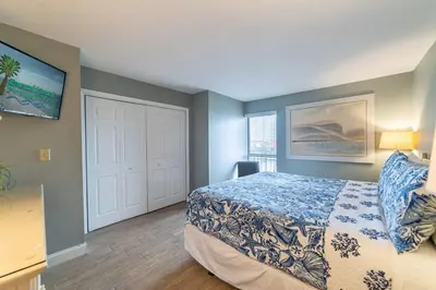 a bedroom with a bed and a white door at Edgewater 1-0303 'Salty Sunsets' in Panama City Beach