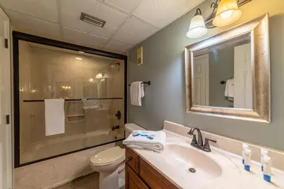 a bathroom with a sink and a toilet and a mirror at Edgewater 1-0303 'Salty Sunsets' in Panama City Beach
