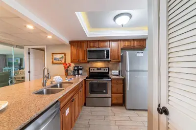 a kitchen with stainless steel appliances and wooden cabinets at Edgewater 1-0303 'Salty Sunsets' in Panama City Beach