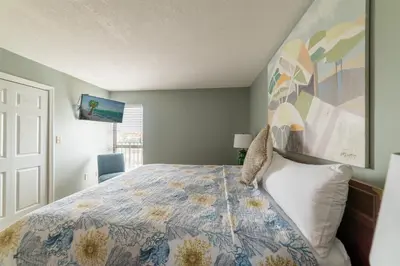 a bedroom with a bed and a painting on the wall at Edgewater 1-0303 'Salty Sunsets' in Panama City Beach