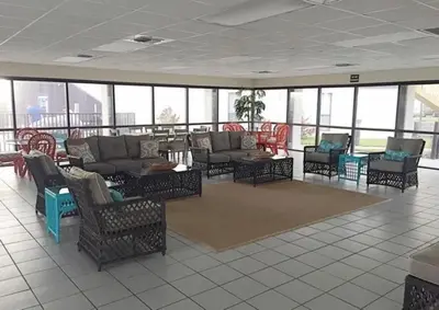 a large room with couches and tables and windows at Sugar Beach B04 'Seaside Escape' in Panama City Beach