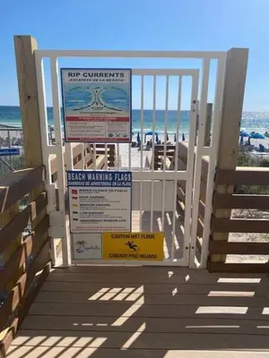 a gate at the beach with a beach warning sign at Seychelles 1602 'Ocean Pearl' in Panama City Beach