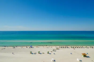 a group of people on a beach with umbrellas at Seychelles 1602 'Ocean Pearl' in Panama City Beach