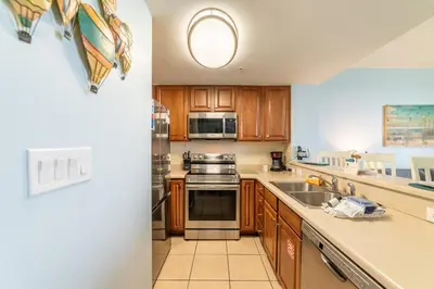 a kitchen with wooden cabinets and stainless steel appliances at Seychelles 1602 'Ocean Pearl' in Panama City Beach