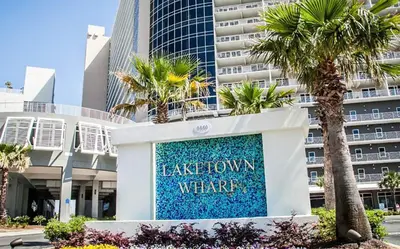 a sign in front of a building with palm trees at Laketown Wharf 816 'Tasty Waves PCB' in Panama City Beach
