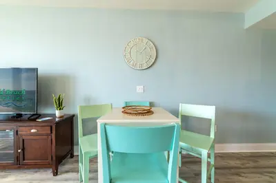 a table with chairs and a clock on a wall at Laketown Wharf 816 'Tasty Waves PCB' in Panama City Beach
