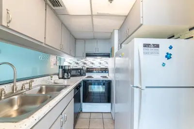 a kitchen with a sink and a refrigerator at Sunbird 0503W 'Big O's Condo' in Panama City Beach