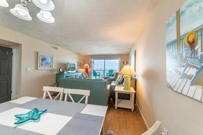 a living room with a table and a dining room at Regency Towers 0407 'The Memory Maker' in Panama City Beach