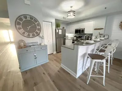 a kitchen with a large clock on the wall at Shores of Panama 1925 'Sunset Shores' in Panama City Beach