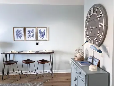a desk and stools in a room with a clock on the wall at Shores of Panama 1925 'Sunset Shores' in Panama City Beach