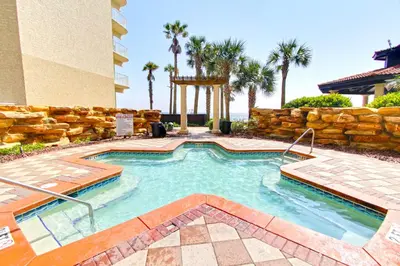 a swimming pool in a resort with a stone wall at Shores of Panama 1925 'Sunset Shores' in Panama City Beach