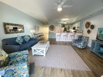 a living room with a blue couch and a kitchen at Shores of Panama 1925 'Sunset Shores' in Panama City Beach