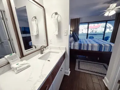 a bathroom with a sink and a bedroom with a bed at Edgewater Villa 0608 'Sunny by the Sea' in Panama City Beach