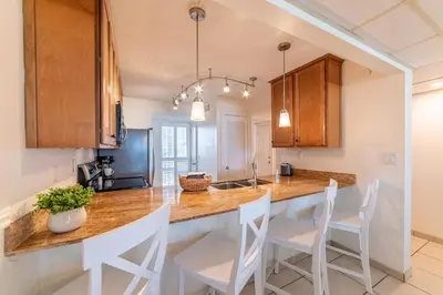 a kitchen with a large island in a kitchen with white chairs at Edgewater 2-0203 'Beach Days' in Panama City Beach