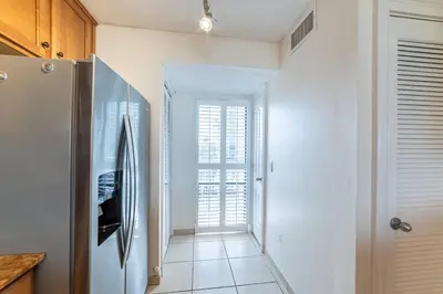 a kitchen with a refrigerator and a hallway with a window at Edgewater 2-0203 'Beach Days' in Panama City Beach
