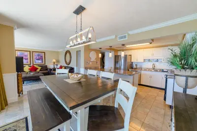 a kitchen and living room with a wooden table and chairs at Edgewater 2-1106 'Hidden Pearl' in Panama City Beach