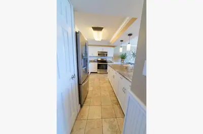 a kitchen with white cabinets and a tile floor at Edgewater 2-1106 'Hidden Pearl' in Panama City Beach