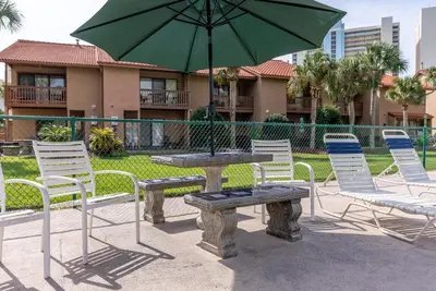 a table and chairs with an umbrella and a bench at Gulf Highlands-Sunset On The Gulf in Panama City Beach